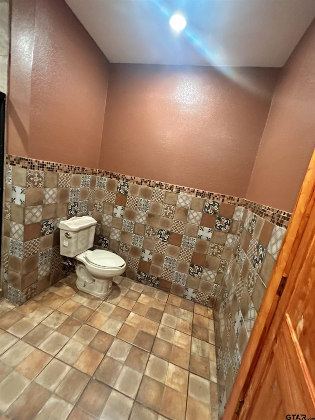 bathroom with toilet and tile walls