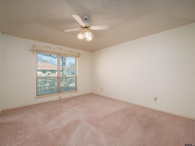 empty room with a textured ceiling, carpet floors, ceiling fan, and baseboards