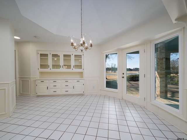 unfurnished dining area with a wainscoted wall, a decorative wall, and light tile patterned flooring