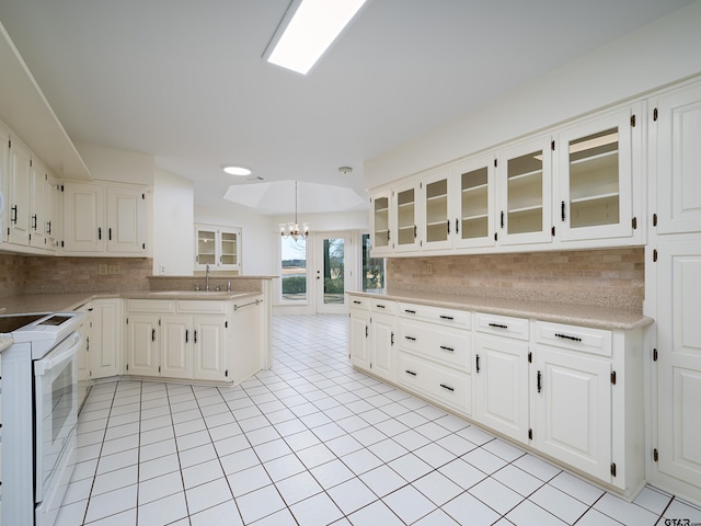 kitchen featuring white electric stove, light countertops, backsplash, and glass insert cabinets