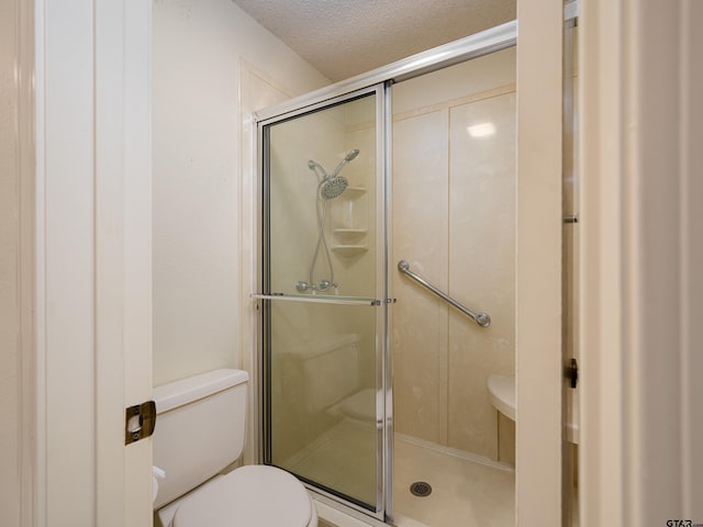 full bathroom with a shower stall, toilet, and a textured ceiling