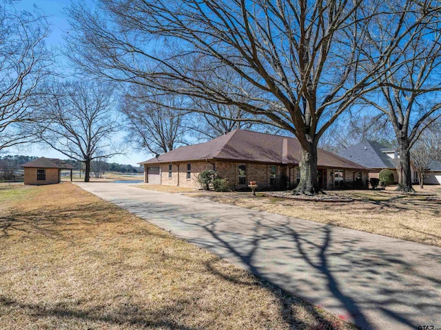 ranch-style home with brick siding, a front lawn, and an outdoor structure