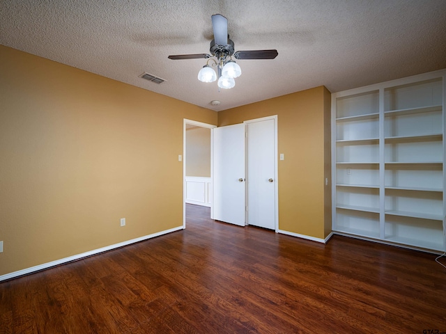 unfurnished bedroom featuring a textured ceiling, ceiling fan, wood finished floors, visible vents, and baseboards