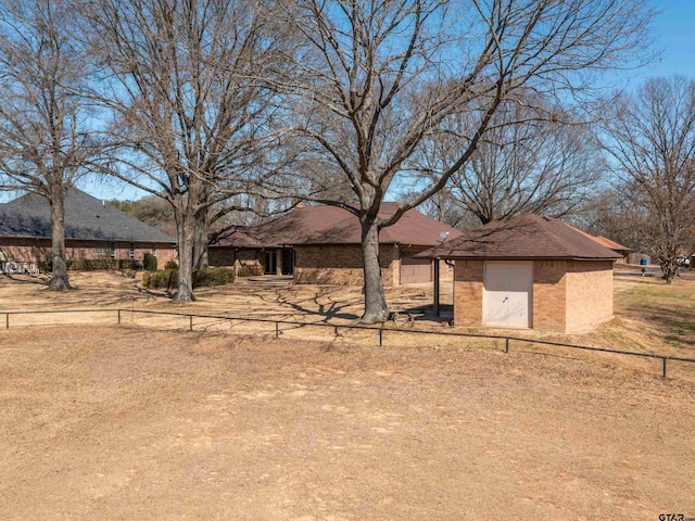 view of front of house featuring an outbuilding, a shed, brick siding, and fence