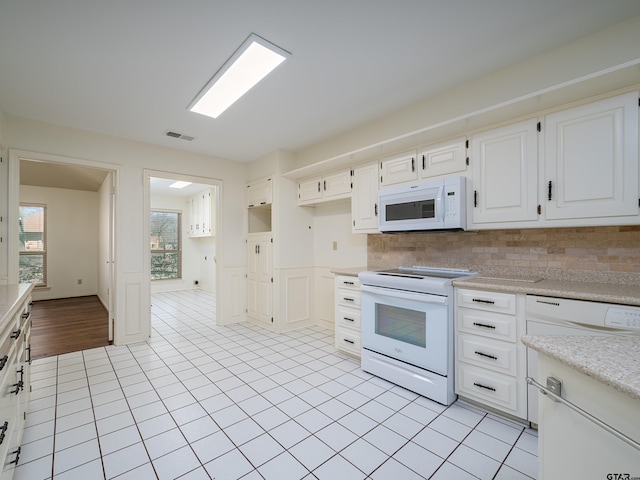 kitchen featuring white appliances, visible vents, white cabinets, decorative backsplash, and light countertops