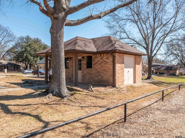 view of side of property featuring an attached garage, brick siding, a shingled roof, and fence