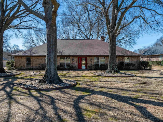 single story home with roof with shingles, a chimney, and brick siding