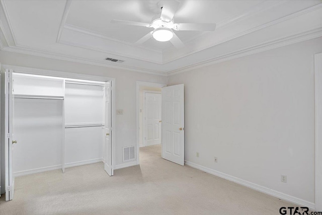 unfurnished bedroom with light carpet, ceiling fan, and a tray ceiling