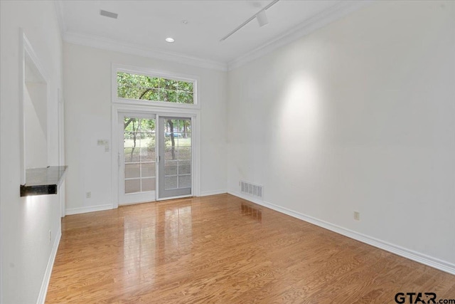 empty room with light hardwood / wood-style flooring and crown molding