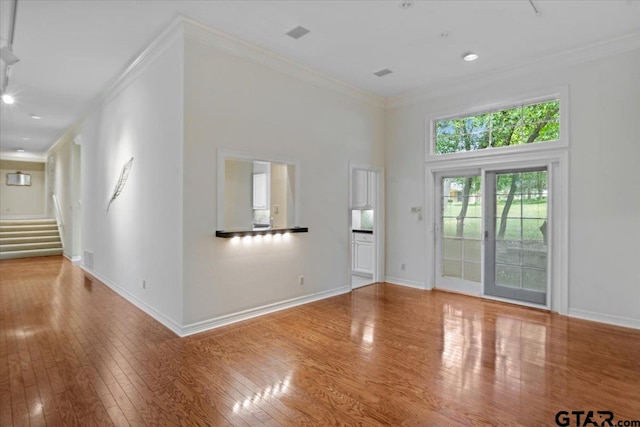 unfurnished living room with a high ceiling, wood-type flooring, and ornamental molding