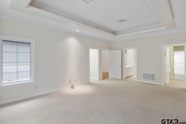 unfurnished bedroom featuring connected bathroom, light carpet, ornamental molding, and a raised ceiling