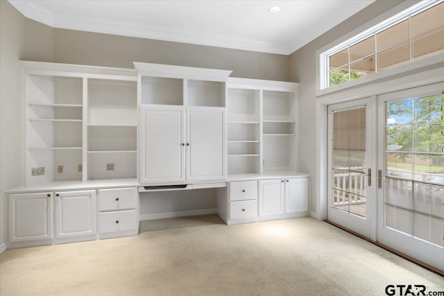 unfurnished office featuring light colored carpet, built in desk, and crown molding