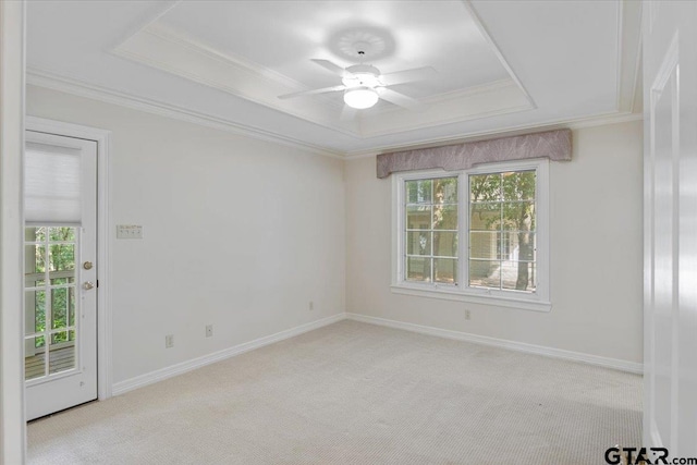 empty room featuring a wealth of natural light, ceiling fan, light carpet, and a tray ceiling