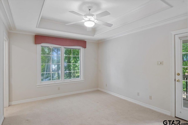 carpeted empty room featuring ceiling fan, crown molding, and a tray ceiling