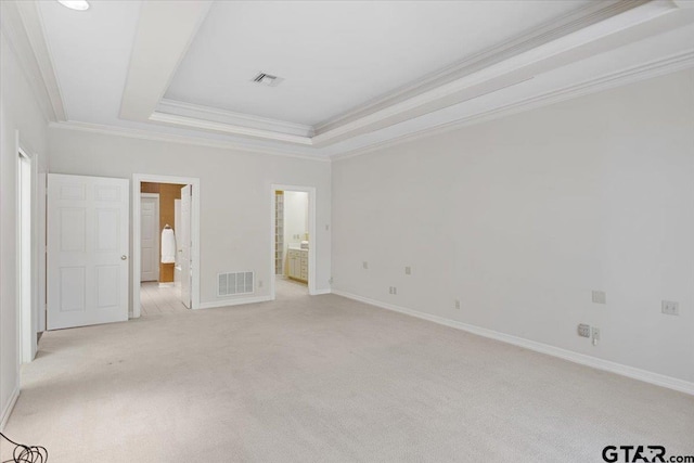 unfurnished bedroom with connected bathroom, a tray ceiling, light colored carpet, and ornamental molding