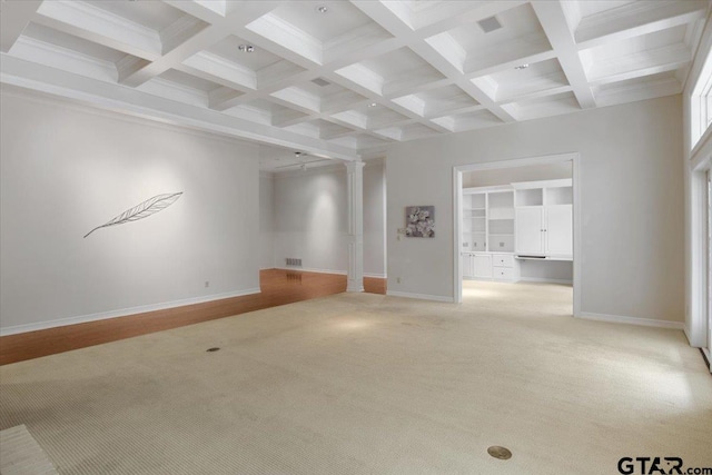 empty room with beamed ceiling, coffered ceiling, light carpet, and decorative columns