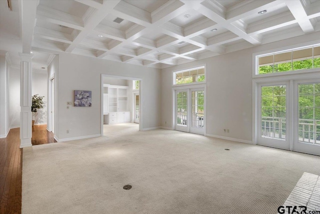 unfurnished living room featuring ornate columns, french doors, hardwood / wood-style flooring, and a high ceiling