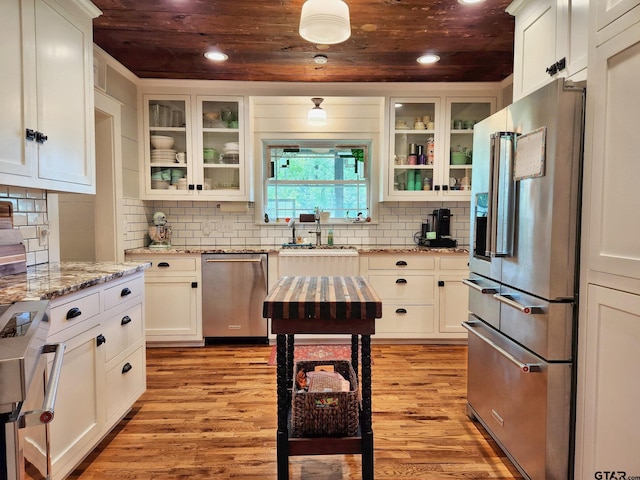 kitchen with light stone counters, stainless steel appliances, sink, light hardwood / wood-style floors, and white cabinets