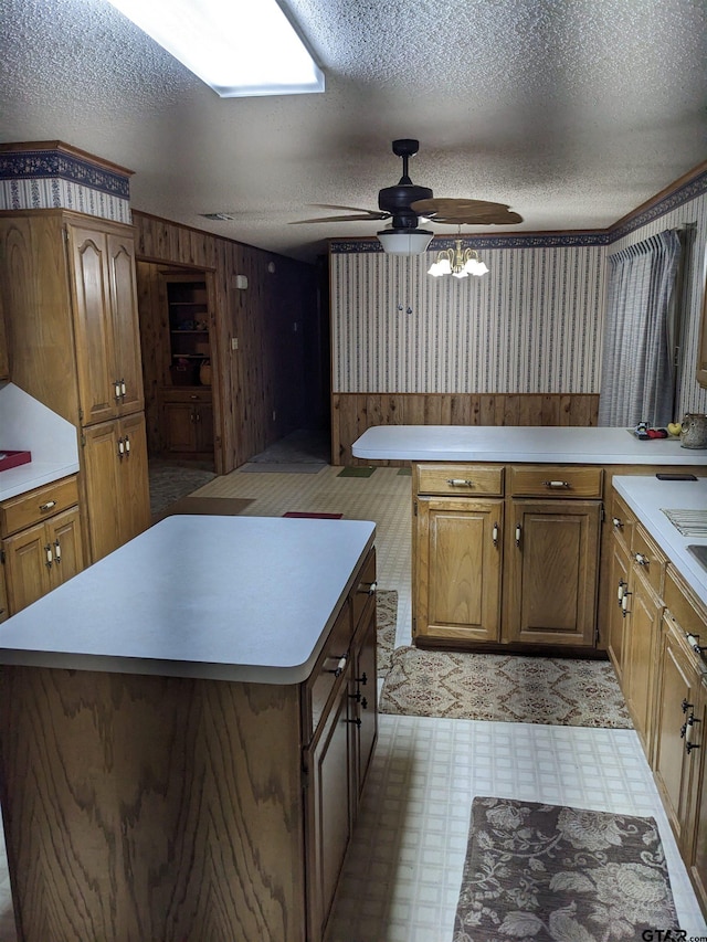 kitchen featuring a kitchen island, a textured ceiling, wood walls, and ceiling fan