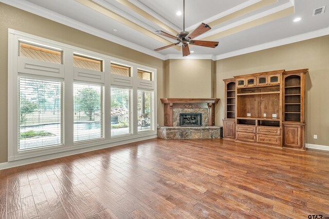 2441 Fm 2685, Gilmer, TX 75644 - unfurnished living room with a ceiling fan, a stone fireplace, wood finished floors, crown molding, and baseboards