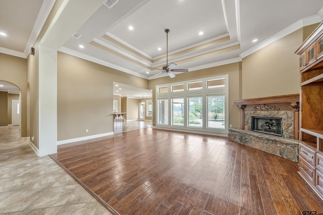 2441 Fm 2685, Gilmer, TX 75644 - unfurnished living room featuring a stone fireplace, ceiling fan, ornamental molding, light wood finished floors, and arched walkways