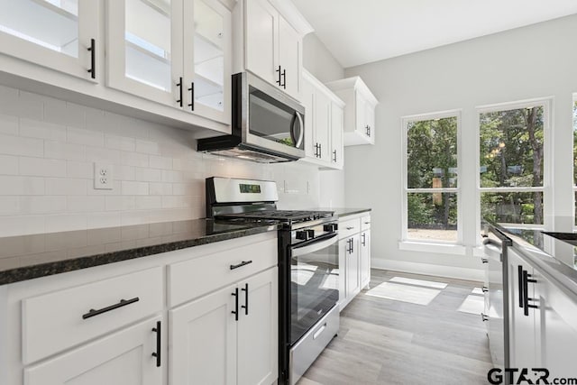 16330 Crossing Cir, Lindale, TX 75771 - kitchen featuring appliances with stainless steel finishes, white cabinetry, dark stone countertops, glass insert cabinets, and decorative backsplash