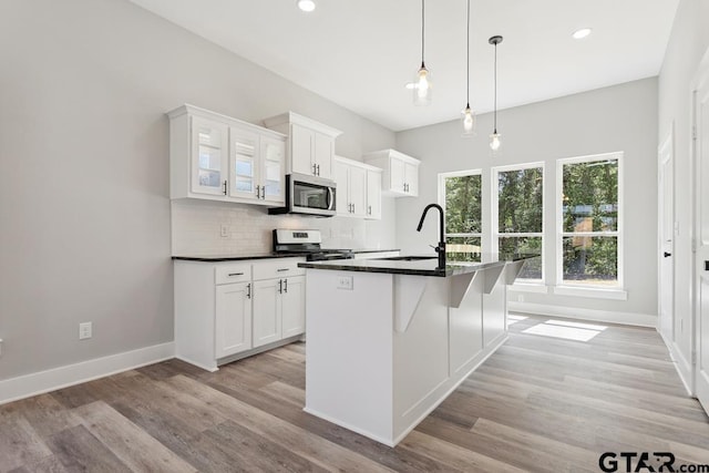 16330 Crossing Cir, Lindale, TX 75771 - kitchen featuring stainless steel microwave, range, backsplash, light wood-style flooring, and dark countertops