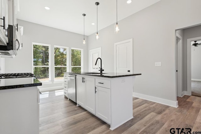 16330 Crossing Cir, Lindale, TX 75771 - kitchen featuring stainless steel appliances, white cabinets, light wood-style flooring, decorative light fixtures, and an island with sink