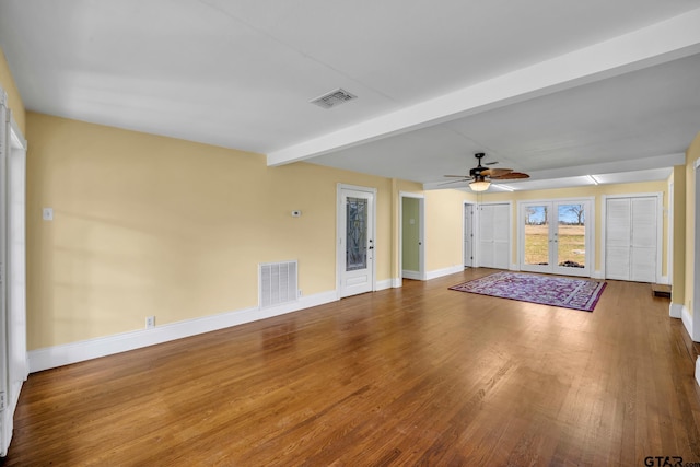 386 Fm 1711, Jacksonville, TX 75766 - unfurnished living room featuring a ceiling fan, visible vents, wood finished floors, baseboards, and beam ceiling