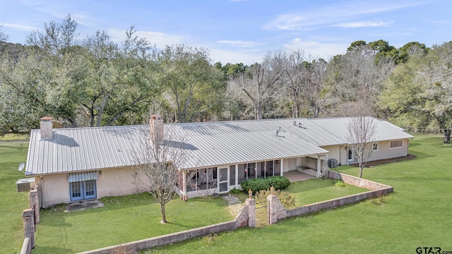 386 Fm 1711, Jacksonville, TX 75766 - back of house with a sunroom, a yard, metal roof, brick siding, and a chimney