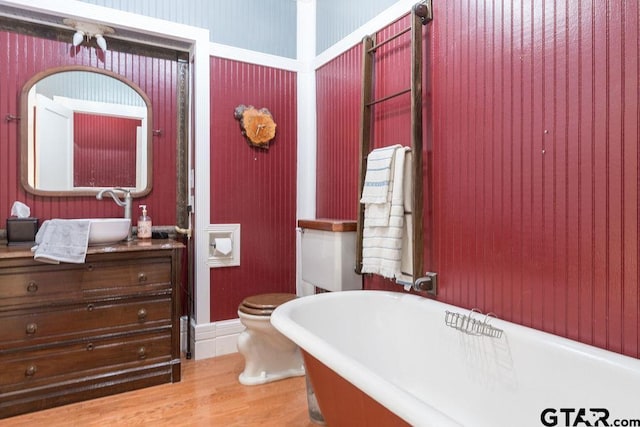 bathroom with hardwood / wood-style floors, a bath, vanity, and toilet