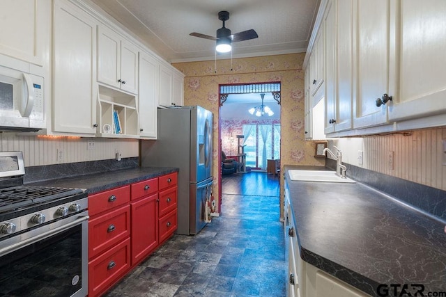 kitchen with ceiling fan with notable chandelier, white cabinets, sink, ornamental molding, and appliances with stainless steel finishes