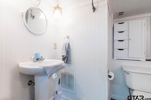 bathroom with wood walls and toilet