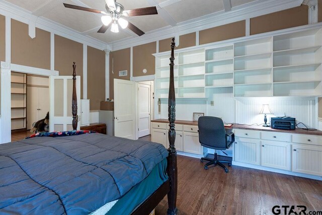 bedroom featuring dark wood-type flooring, ceiling fan, crown molding, a closet, and built in desk