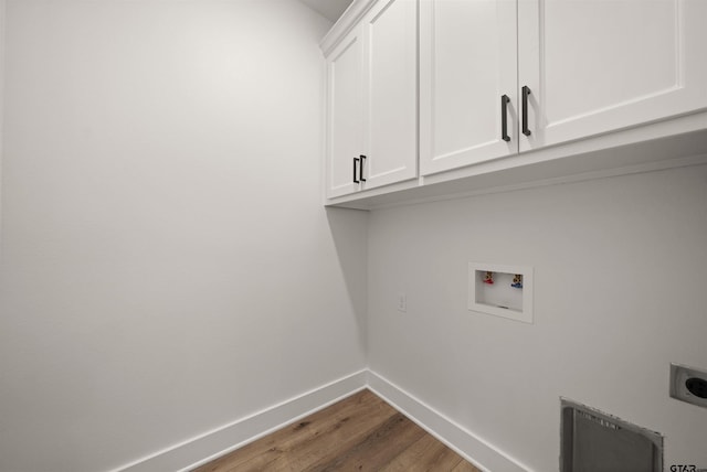 clothes washing area featuring dark hardwood / wood-style flooring, hookup for a washing machine, electric dryer hookup, and cabinets