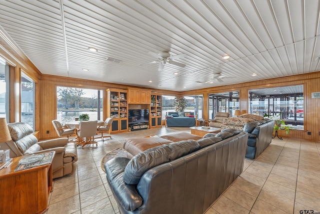 tiled living room featuring ceiling fan, wooden ceiling, and wood walls