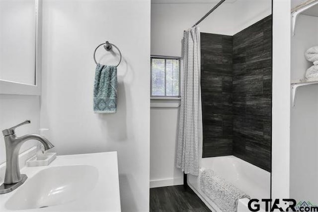 full bathroom featuring baseboards, a sink, and wood finished floors