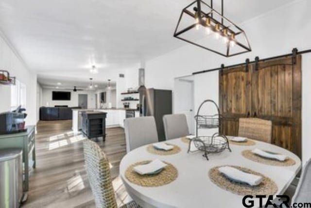 dining area featuring a barn door and wood finished floors