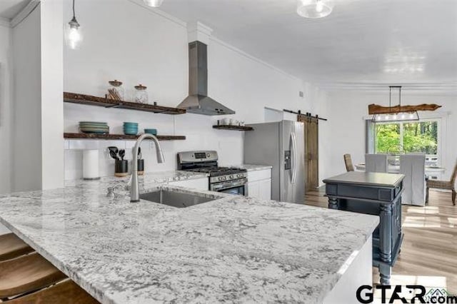 kitchen with open shelves, a barn door, wall chimney exhaust hood, a sink, and stainless steel appliances