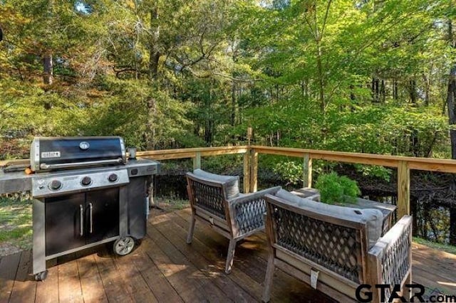 deck featuring grilling area, outdoor lounge area, and a wooded view
