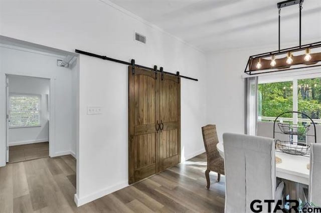 dining space with wood finished floors, plenty of natural light, a barn door, and visible vents