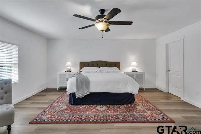 bedroom featuring a ceiling fan, baseboards, and wood finished floors