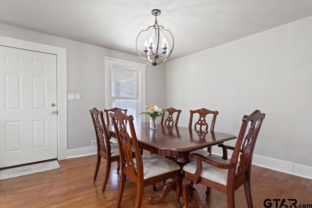 dining area with dark wood-type flooring and a notable chandelier