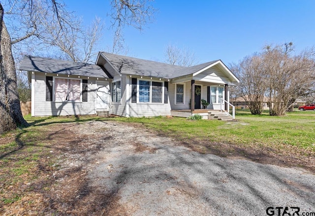 ranch-style house featuring covered porch and a front lawn