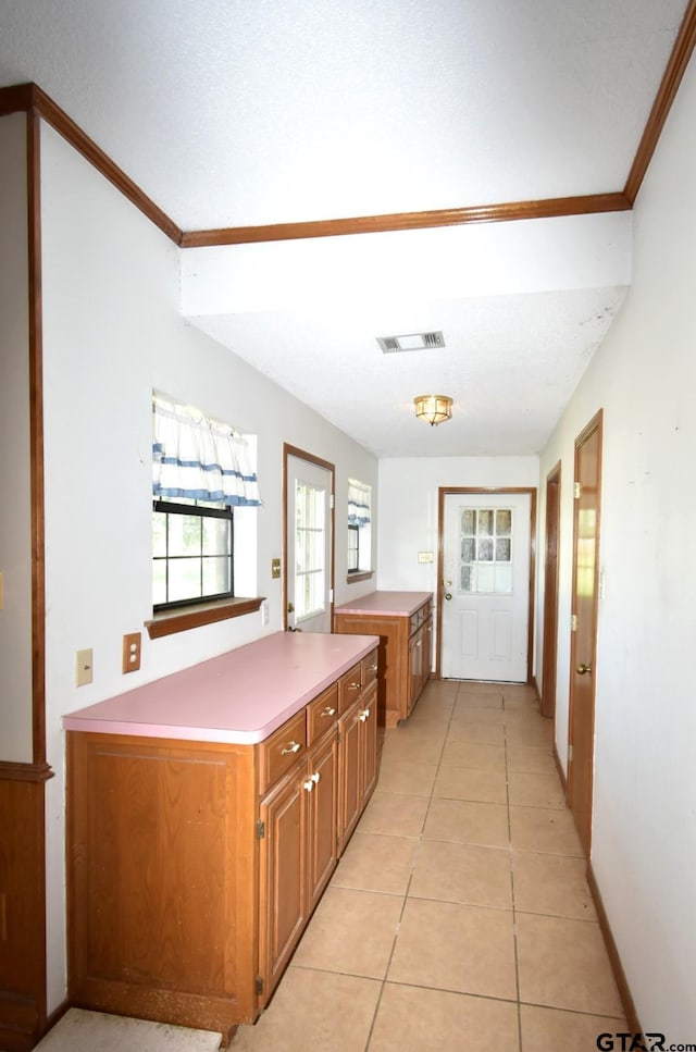 kitchen with crown molding, light tile patterned floors, and kitchen peninsula