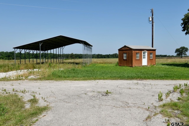 exterior space featuring a carport, a rural view, and a storage unit