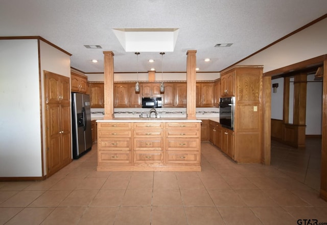 kitchen with ornate columns, an island with sink, sink, ornamental molding, and black appliances