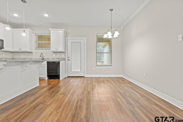 kitchen with pendant lighting, white cabinetry, black appliances, light stone countertops, and light wood-type flooring