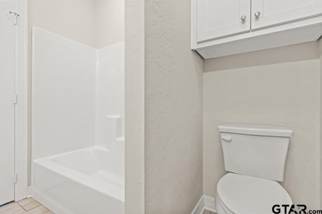 bathroom featuring hardwood / wood-style flooring, shower / washtub combination, and toilet