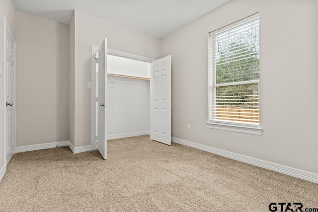 unfurnished bedroom featuring light colored carpet, a closet, and multiple windows